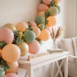 Matte pastel balloon garland, eucalyptus leaves, and fairy lights setup, showcasing simple balloon decoration ideas at home on a white table.